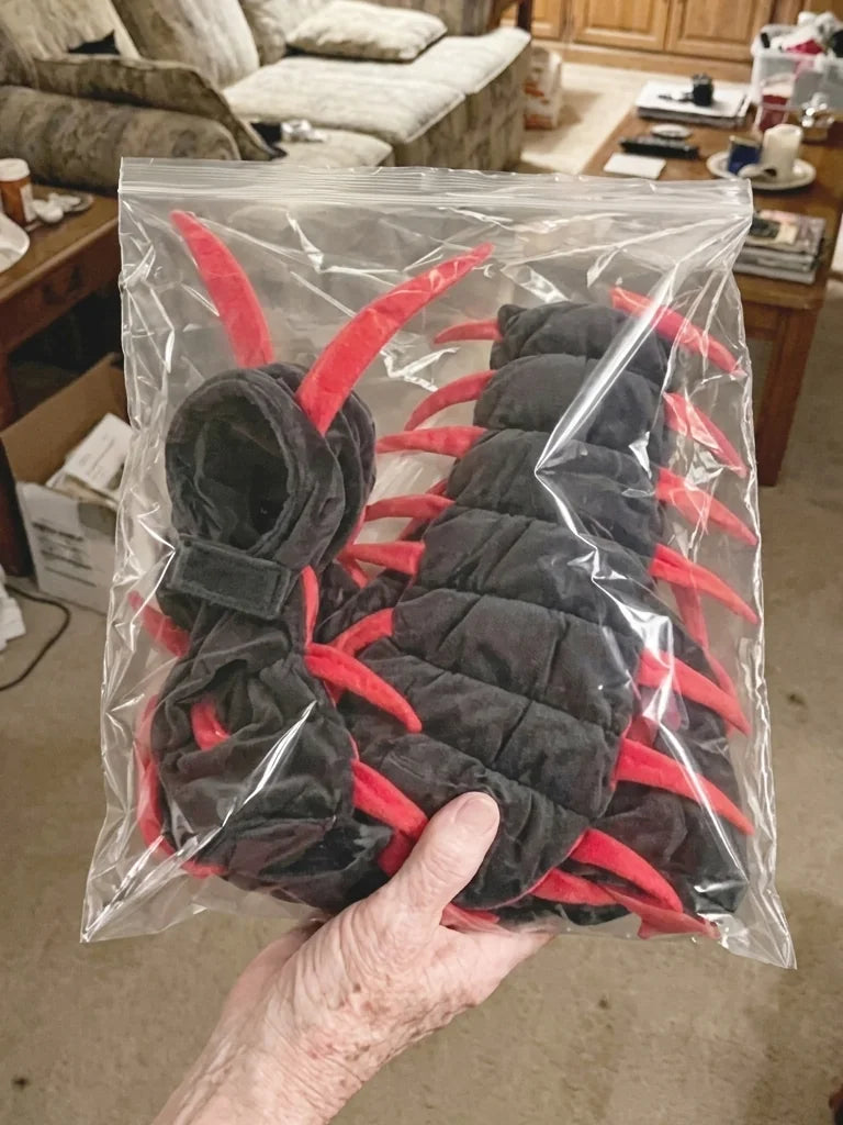 Hand holding the centipede cat costume in a clear bag