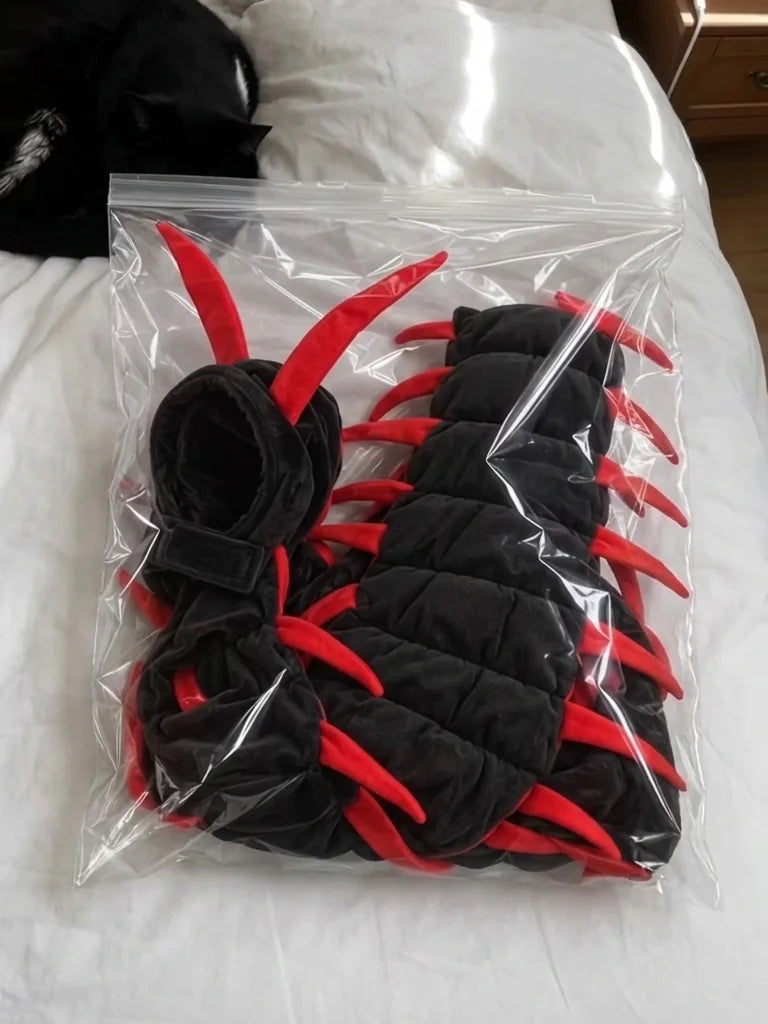 Centipede cat costume folded in a clear bag on a bed